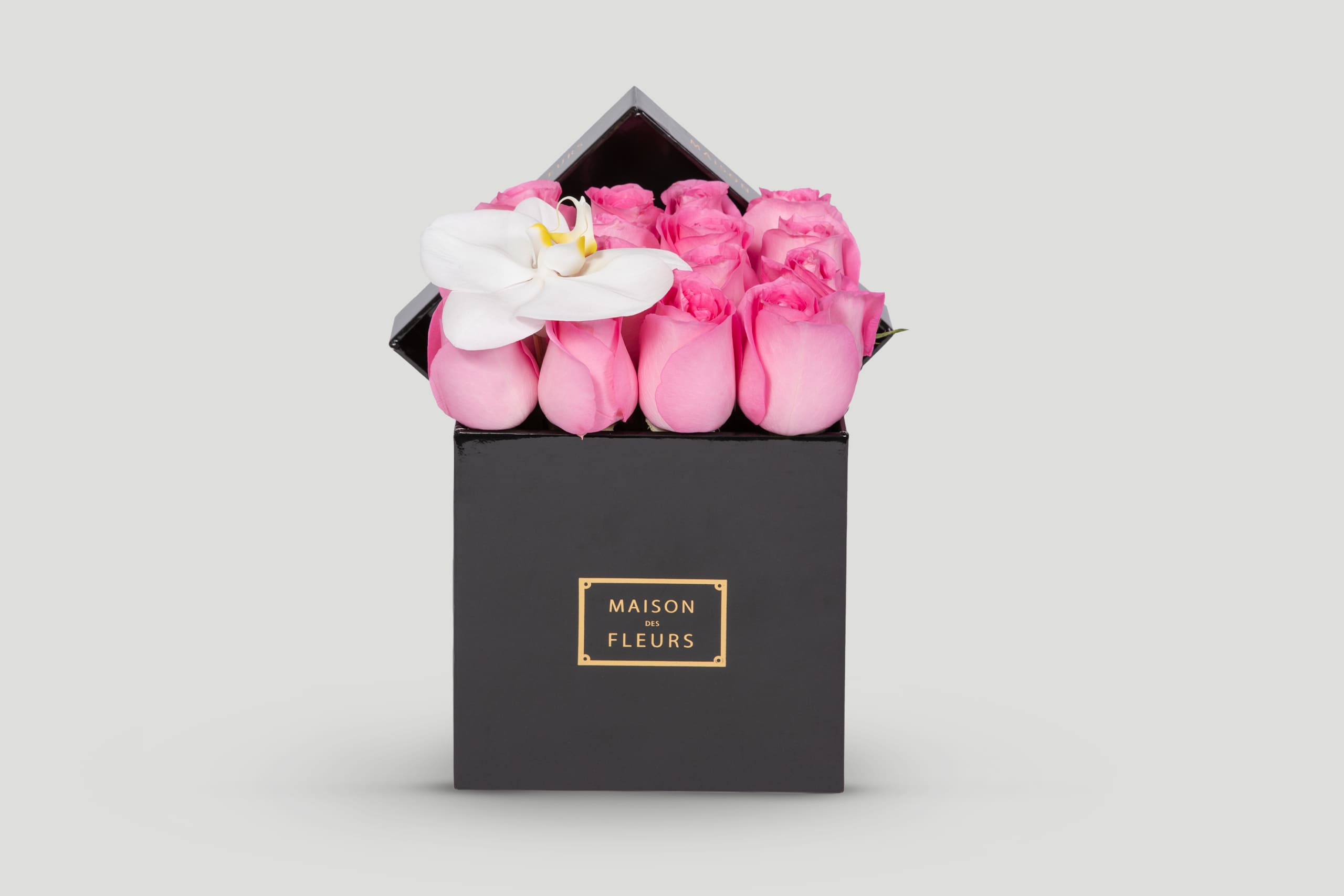 Black Square Box Filled With Pink Roses and a White Orchid