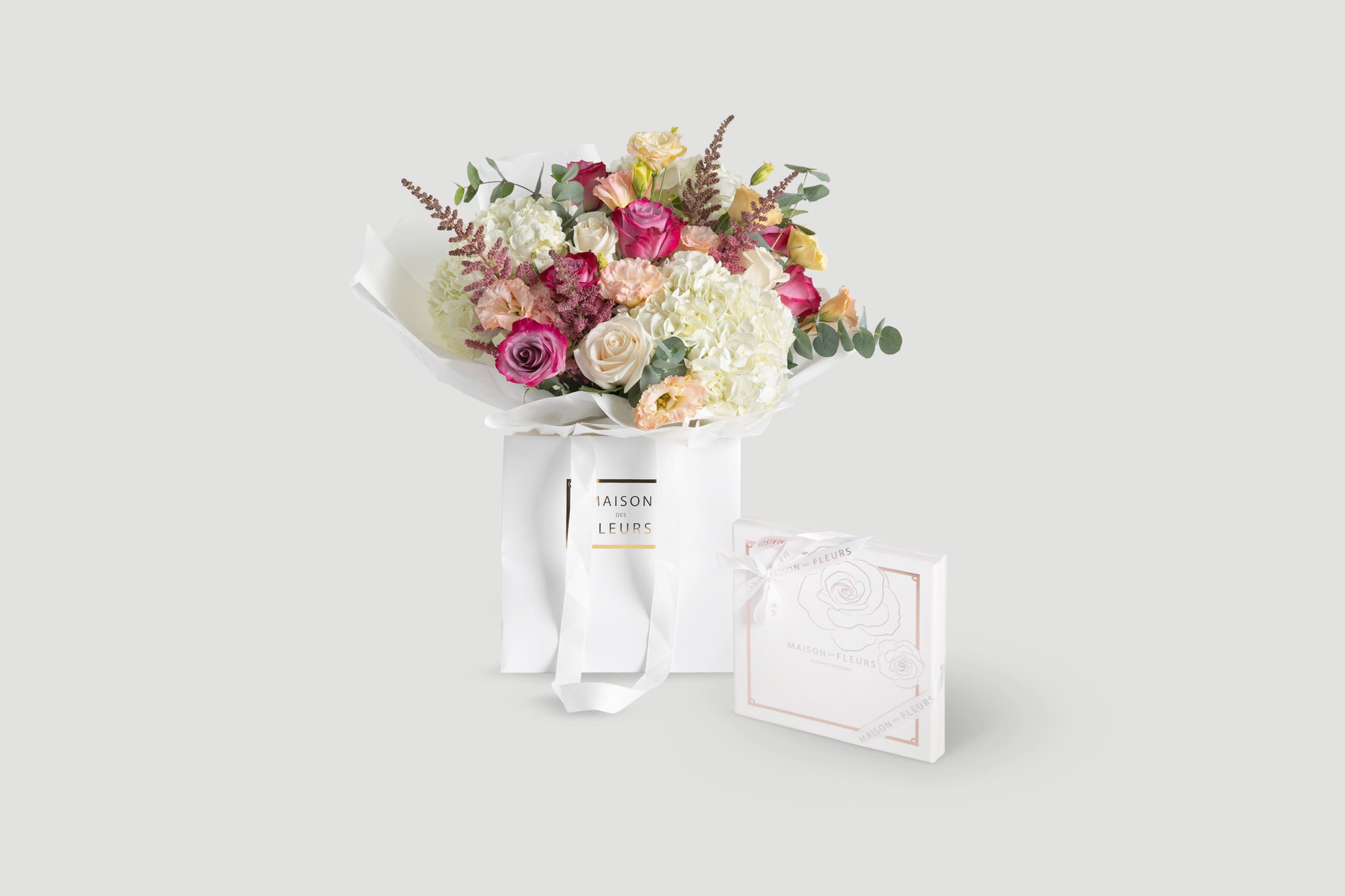 Bouquet of pink, purple, and white flowers with a gift box